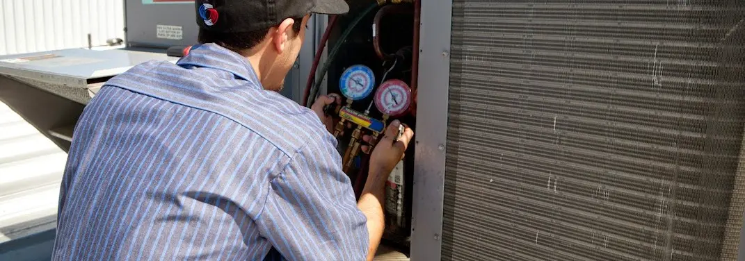 HVAC technician servicing a condenser unit in Alliance