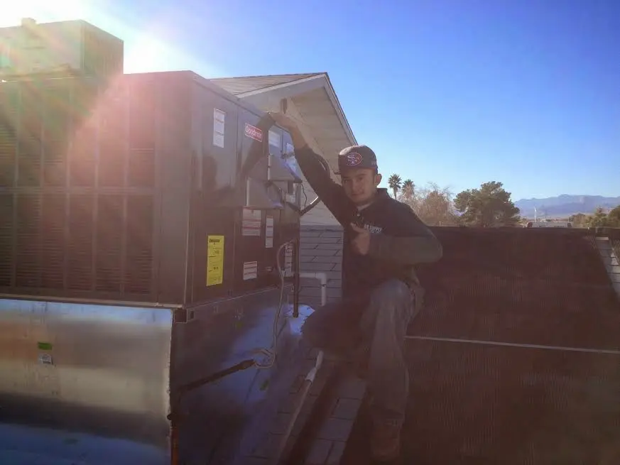HVAC technician performing AC Tune-Up on a rooftop unit in Alliance